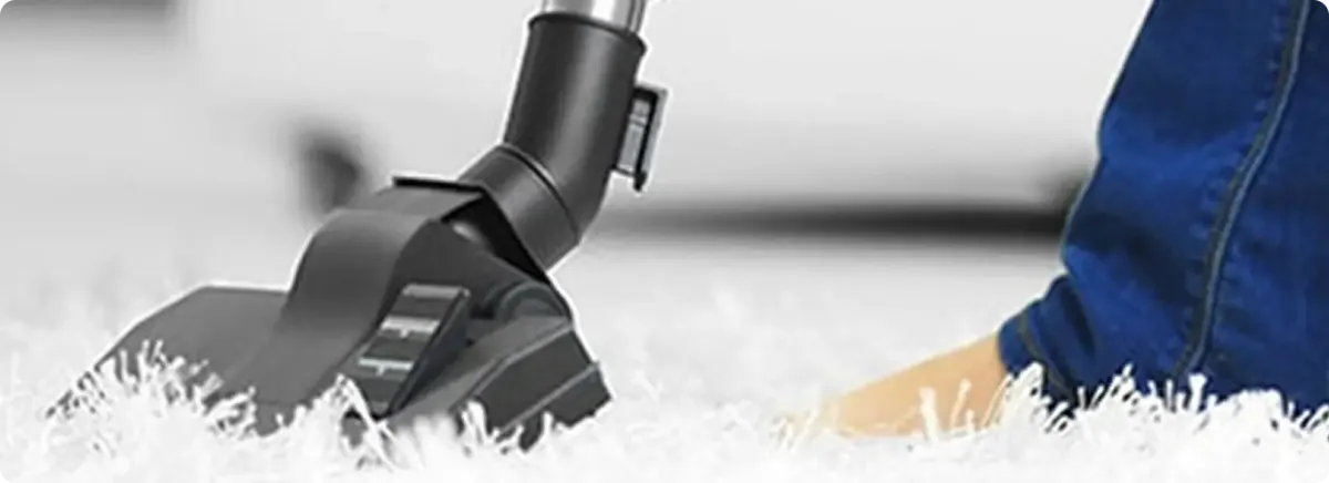 Close-up of a professional vacuuming a white carpet in Berwyn.